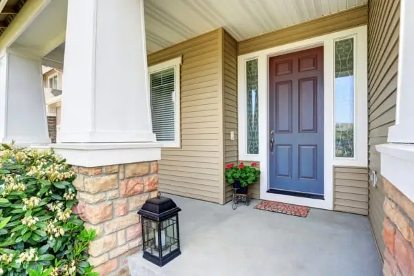 Homeowner Vilma F. smiling beside her new fiberglass entry door installed by Coastal Windows & Exteriors.