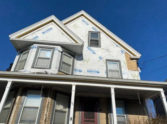 Home exterior under construction with house wrap for vinyl siding installed before siding replacement