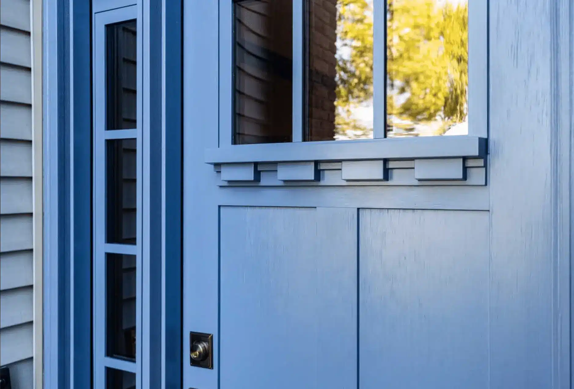 Close-up of a blue front door with glass panels and decorative trim.