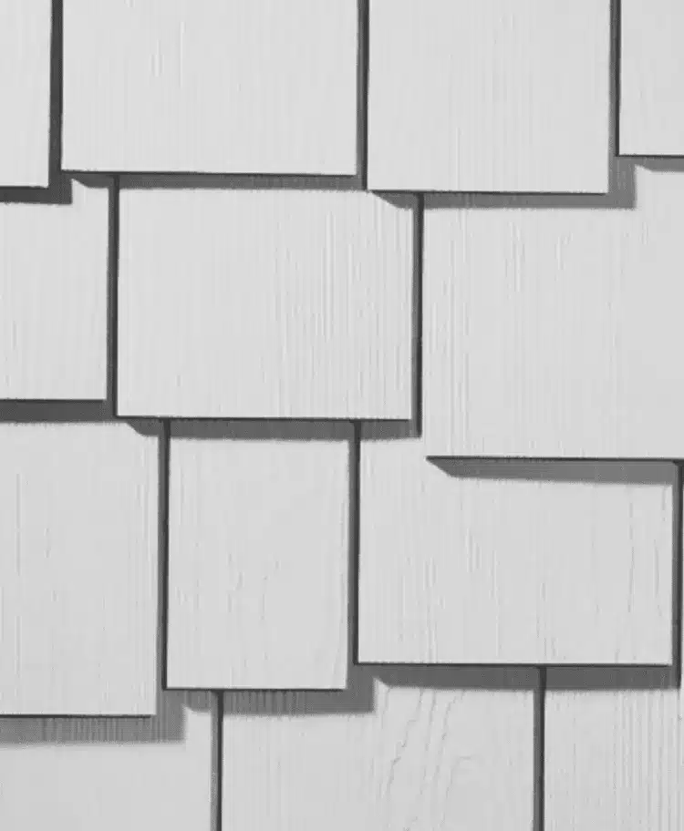 White, rectangular panels with a wood grain texture are staggered in an overlapping pattern, resembling types of James Hardie® siding products. Shadows highlight the separation between the panels, enhancing the geometric, layered design.
