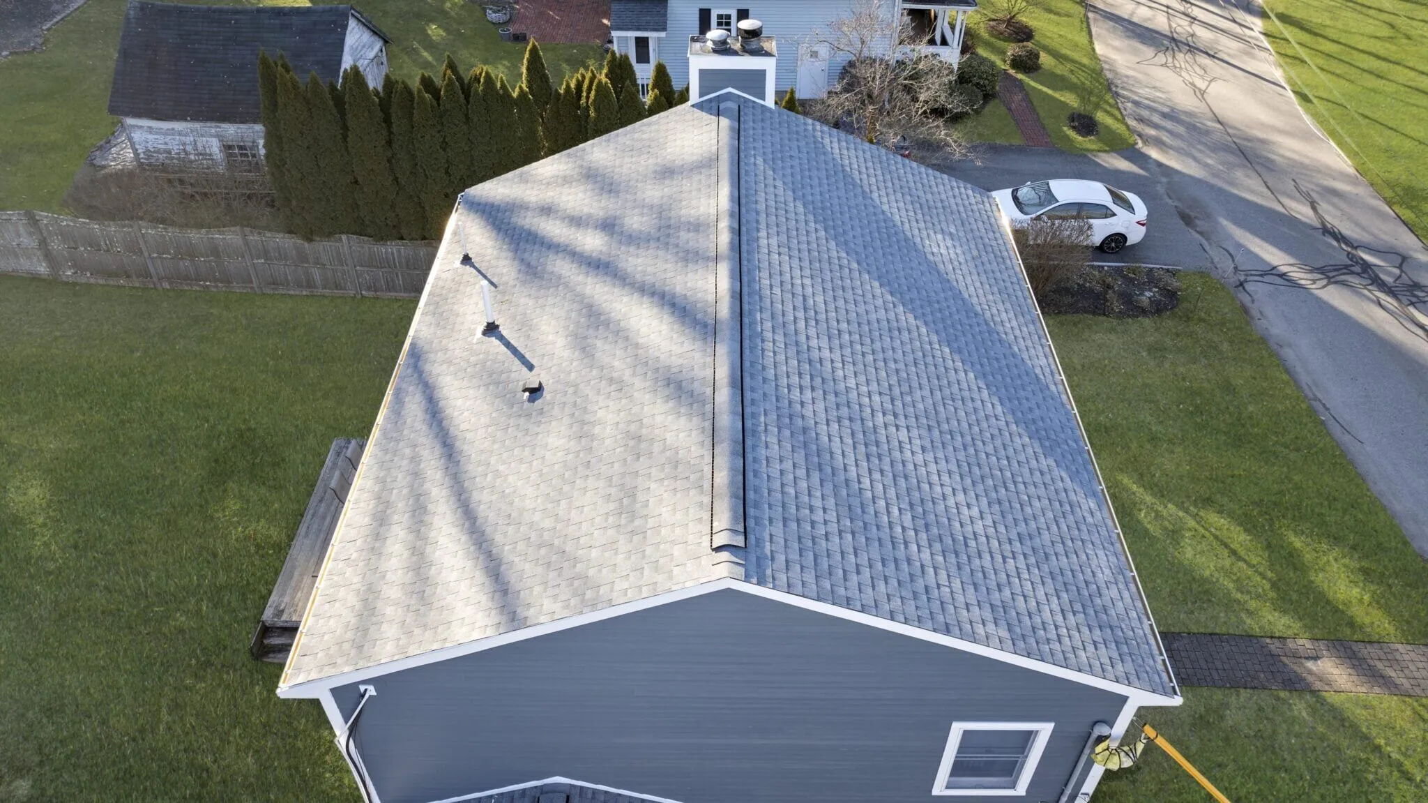 An aerial before-and-after roofing comparison shows the replacement of an aging roof with modern asphalt shingles. Roofing improvements remain one of the most effective high-roi exterior upgrades for protecting a home's structure and value.