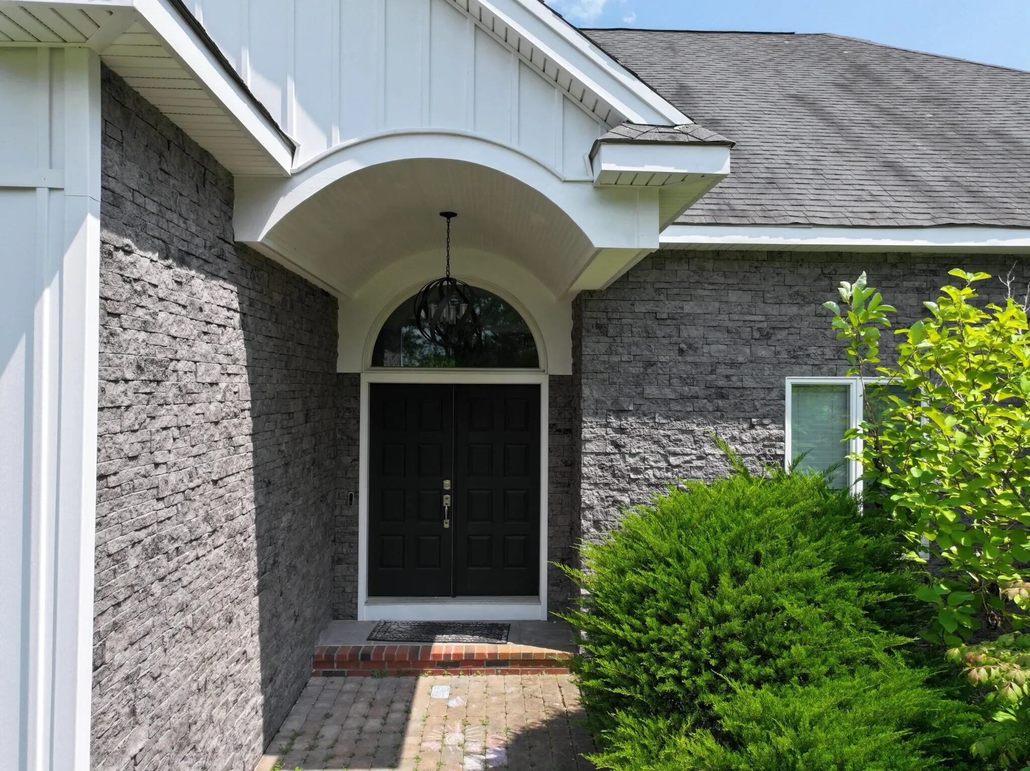 Manufactured stone veneer surrounds this elegant front entrance, creating a premium architectural appearance. Decorative exterior enhancements like stone veneer are attractive high-roi exterior upgrades that elevate curb appeal.